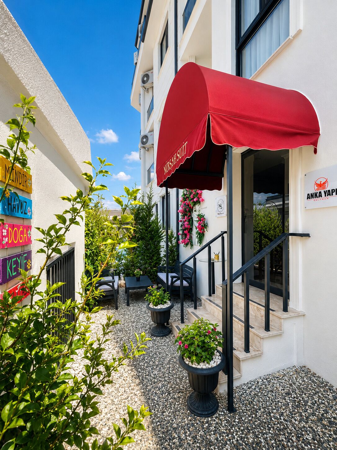 A building with a red awning, outdoor seating, and potted plants.