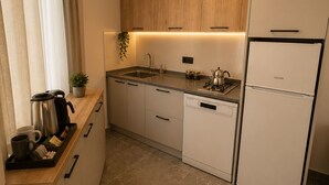 Ett modernt kök med träskåp, en diskho i rostfritt stål, en diskmaskin och ett kylskåp.