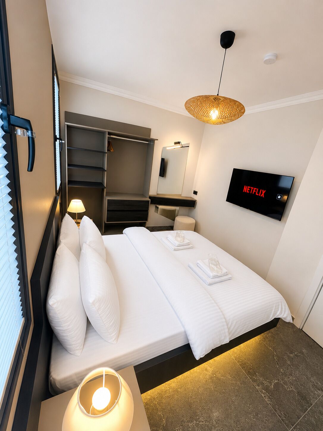 Ein modernes Hotelzimmer mit Bett, Fernseher, Kleiderschrank und Bad.