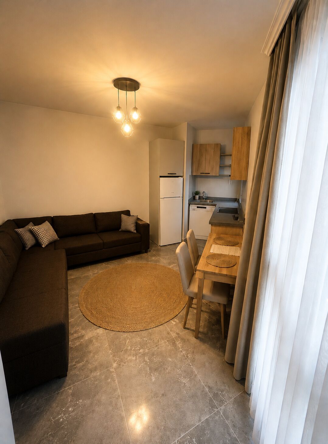 A compact living space with a sofa, a dining table, a kitchen area, and a ceiling light fixture.