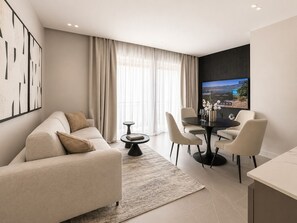 Un soggiorno moderno con un divano, un tavolo da pranzo con sedie, un tavolino e una TV fissata alla parete.