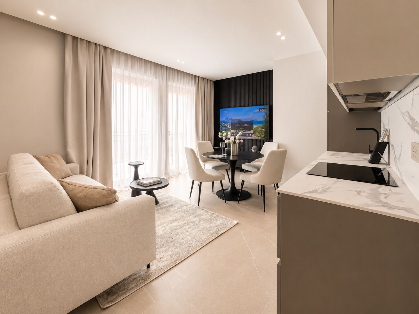 Un soggiorno moderno con un divano, un tavolo da pranzo con sedie, una televisione e un angolo cottura con fornello.