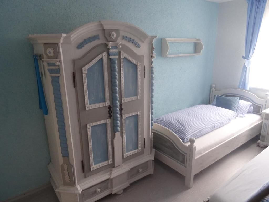 Un dormitorio con cama, armario y ventana con cortinas.
