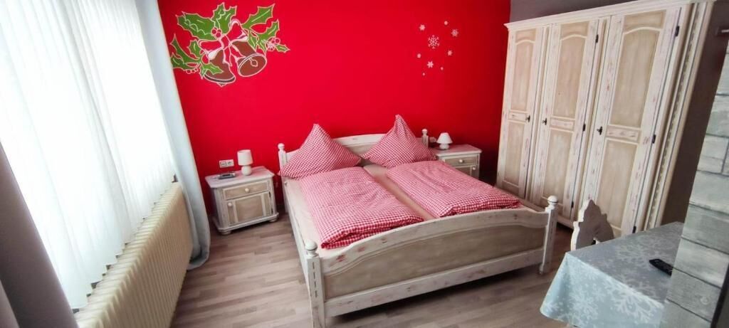 Una camera da letto con un letto in legno, due comodini, un armadio e un termosifone.