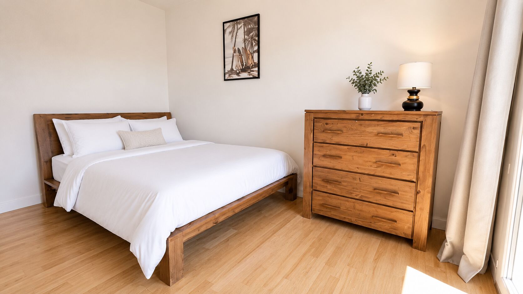 Une chambre avec un lit en bois, une table de chevet avec des tiroirs, une petite plante en pot et un tableau encadré accroché au mur.