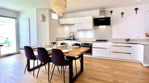 Una cocina moderna con armarios blancos, una mesa de comedor de madera y sillas negras.