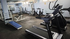 A gym with cardio equipment, weight machines, and a blue mat.