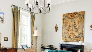 A spacious living room with a green sofa, a glass coffee table, a fireplace, and a large tapestry on the wall. - Large villa very close to Aix-en-Provence (Aix-en-Provence)