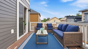 Une terrasse dotée de meubles en osier, d’une table en bois et d’un tapis bleu.