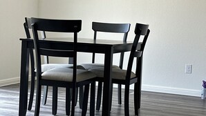 Ruokapöytä neljällä tuolilla, vaaleanvärinen seinä ja puulattia.