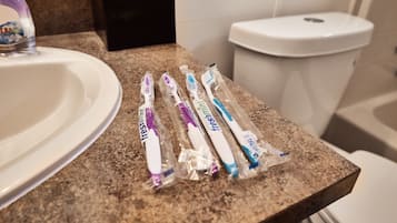 A bathroom sink and toilet with toothbrushes placed on the countertop.