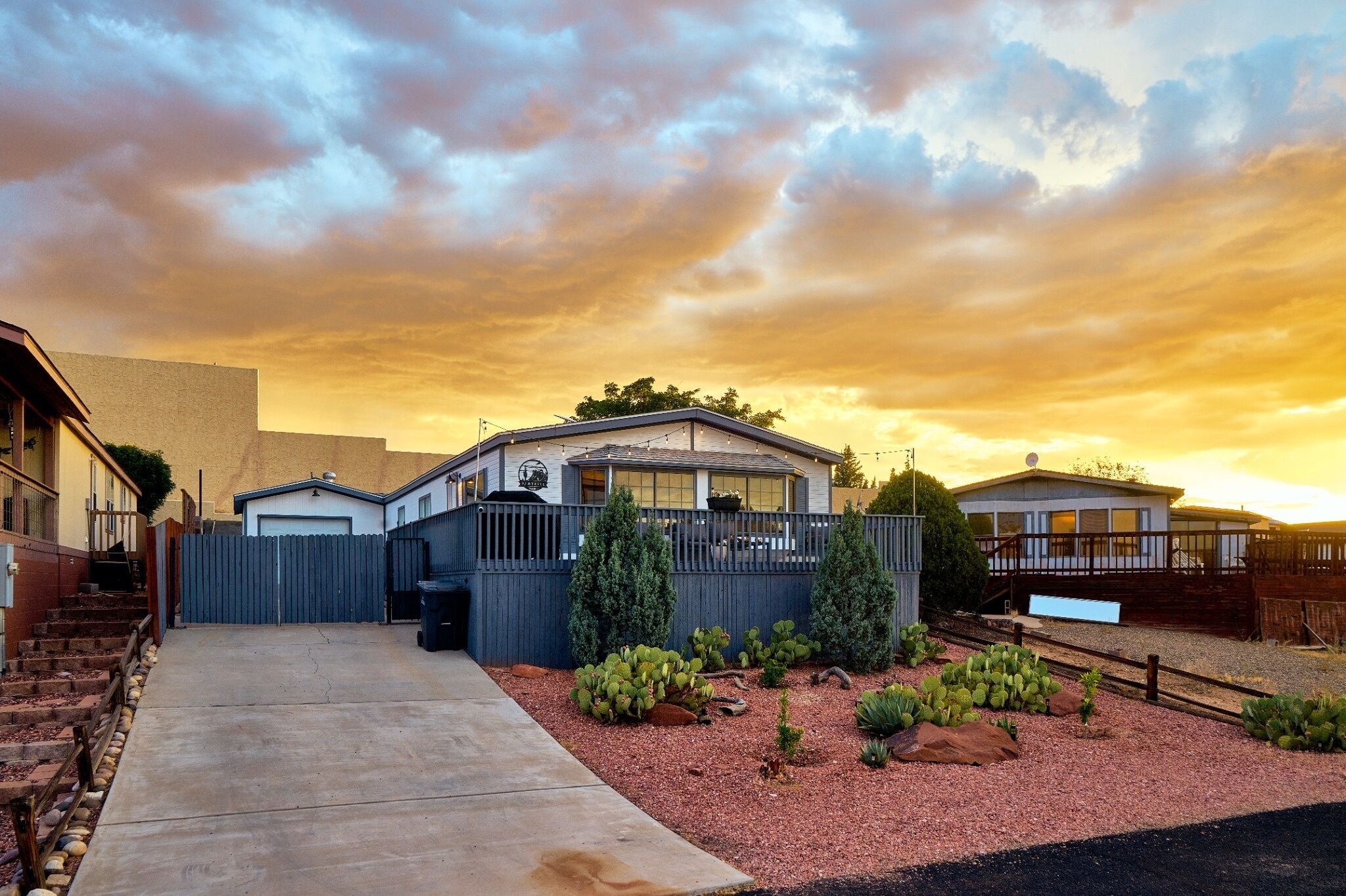 A residential property with a covered patio, a fenced yard with cacti, and a garage.