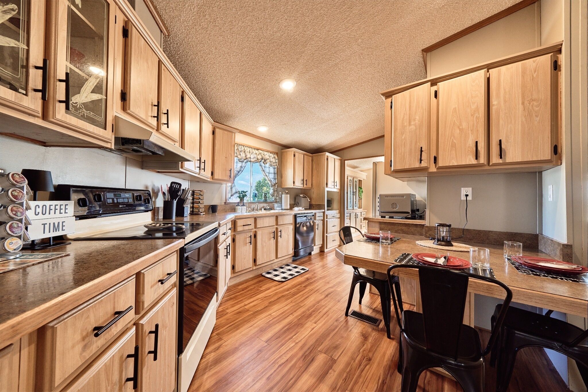 A kitchen with wooden cabinets, a coffee station, and a dining area with chairs and a table.