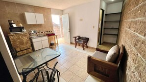 A kitchen with a dining area, a small table, and a chair. There is a microwave, a coffee maker, and a cabinet. - Private room with a kitchenette and parking in downtown Oaxtepec (Oaxtepec)