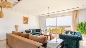 Ein stilvolles Wohnzimmer mit einer Couch, Sesseln, einem Couchtisch und einem großen Fenster mit Blick.