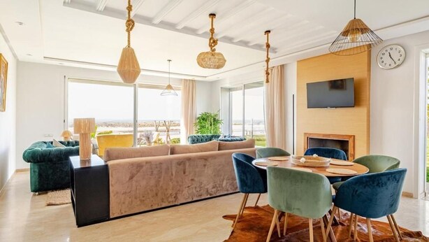 Ein modernes Wohnzimmer mit einer Couch, einem Esstisch, Stühlen, einem Fernseher und einem Kamin.