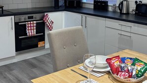 A modern kitchen with white cabinets, a black countertop, and a dining area with a table set for two. - Sleeps 4 • City Centre Gem • Private Rooftop Feel Terrace • Great for Groups (Kingston upon Hull)