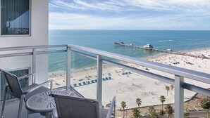 Un balcón con vista a una playa, un muelle y un cielo despejado.