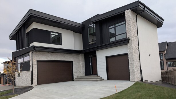 A modern two-story house with a garage, a driveway, and a well-maintained lawn. - New Cozy 2 Bedrooms Basement Apartment (Calgary)