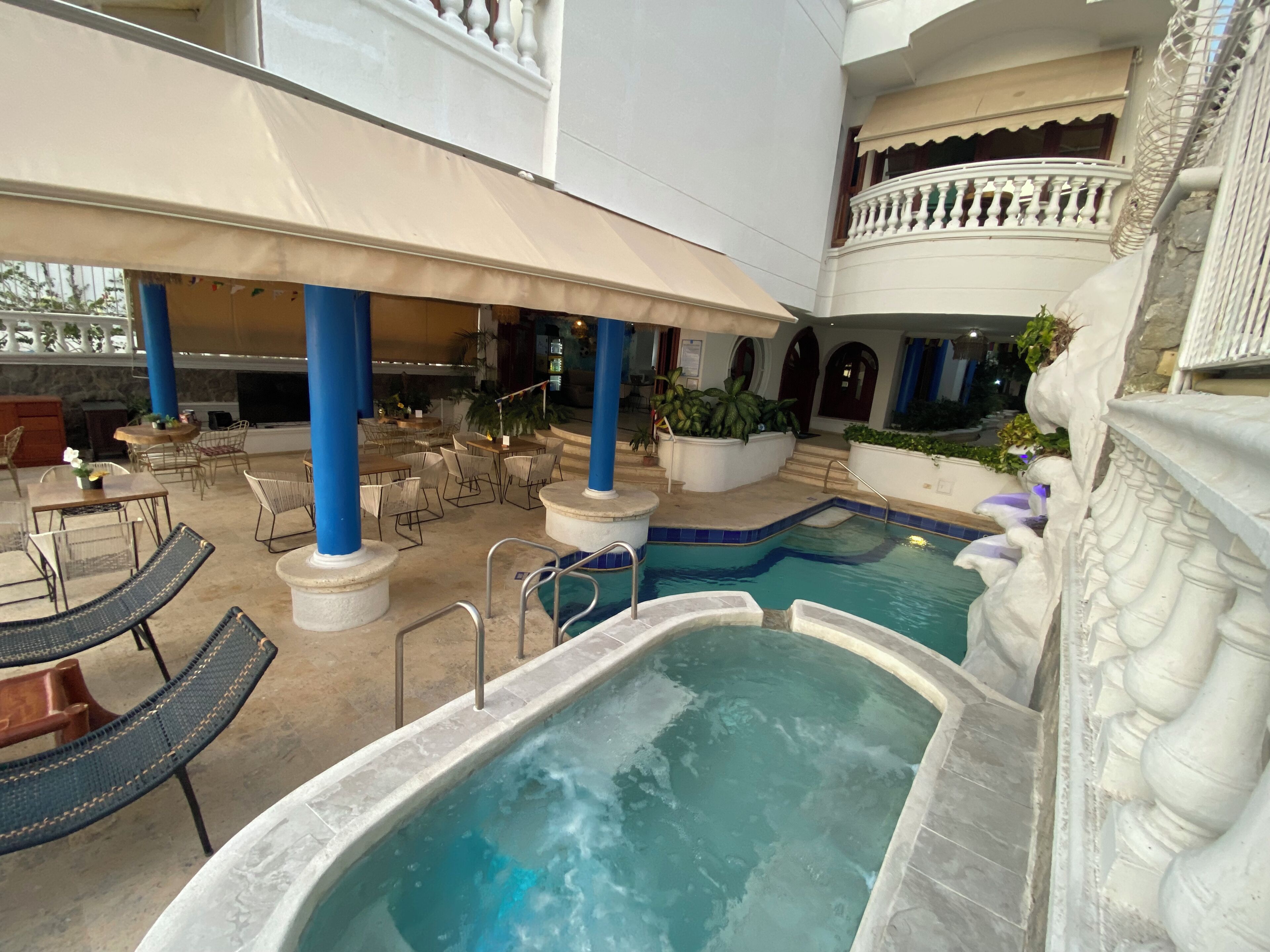 A pool area with lounge chairs and a hot tub.