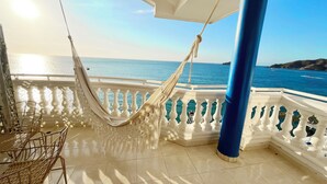 A balcony with a hammock, a chair, and a view of the sea. - Azul Hotel Boutique (Santa Marta)