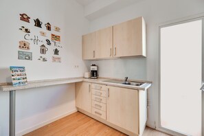 Eine kompakte Küche mit hellen Holzschränken, einer Kaffeemaschine und Wanddekorationen.
