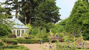A garden with a gazebo, benches, and a variety of plants.