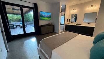 Une chambre à coucher avec un lit, une télévision, une salle de bain avec un miroir et une vue sur l’extérieur.