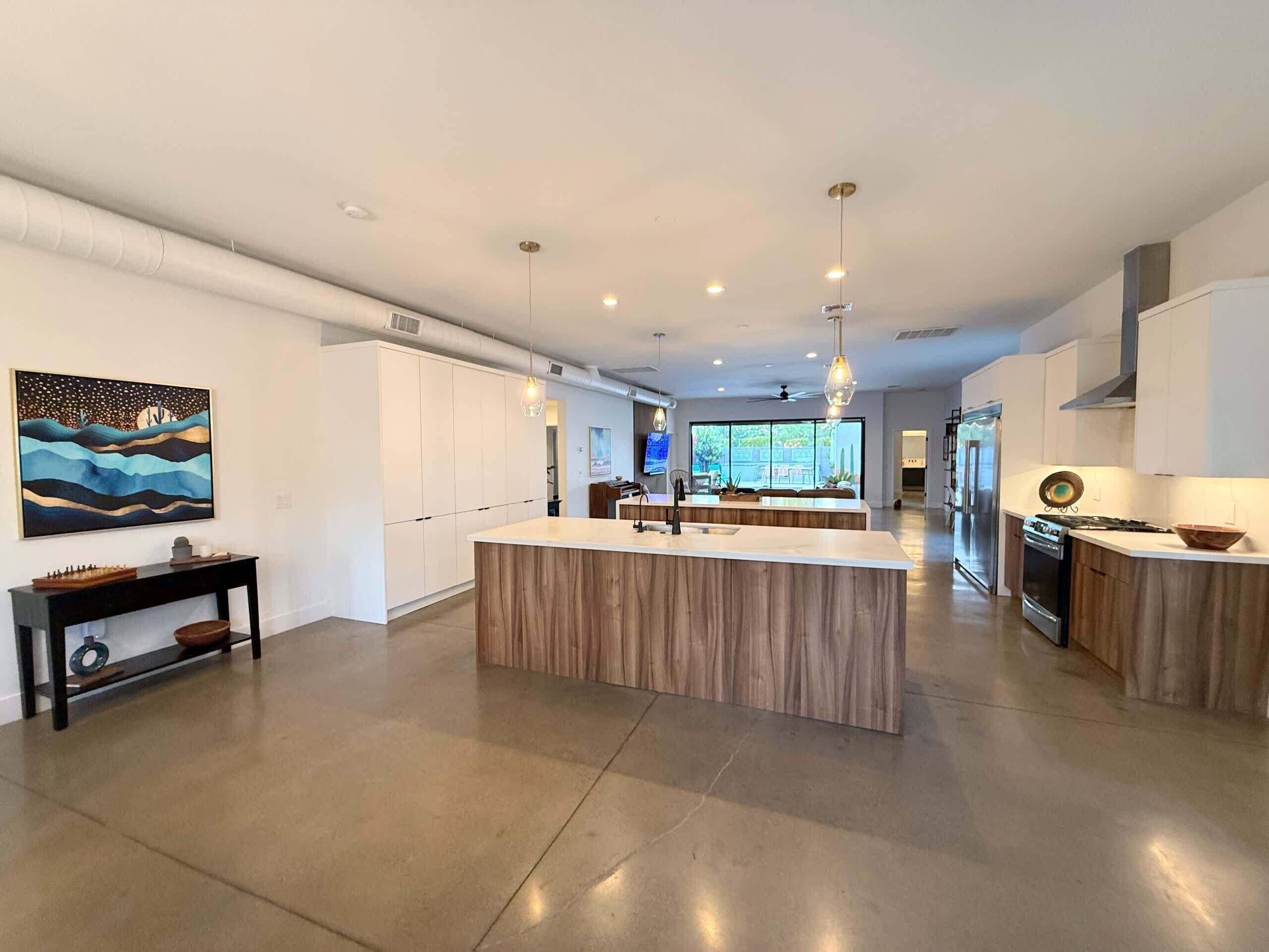 Una cocina moderna con una isla central, armarios blancos e iluminación colgante.