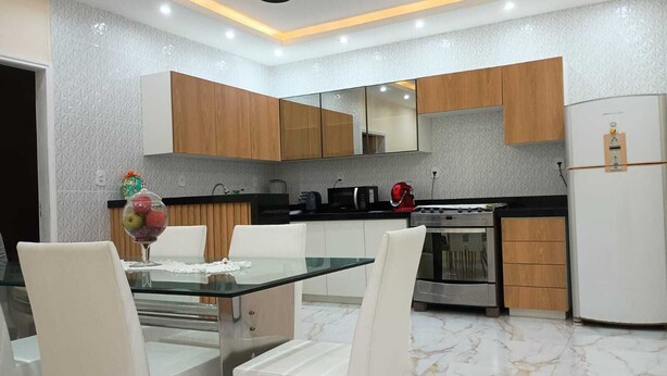 A modern kitchen with wooden cabinets, a glass dining table, and a built-in oven. - Our house in Praia do Futuro, Fortaleza, offers comfort and privacy, just 100 meters from the sea. (Fortaleza)
