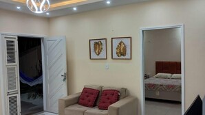 A room with a sofa, a bed, and two framed leaf decorations on the wall. - Our house in Praia do Futuro, Fortaleza, offers comfort and privacy, just 100 meters from the sea. (Fortaleza)