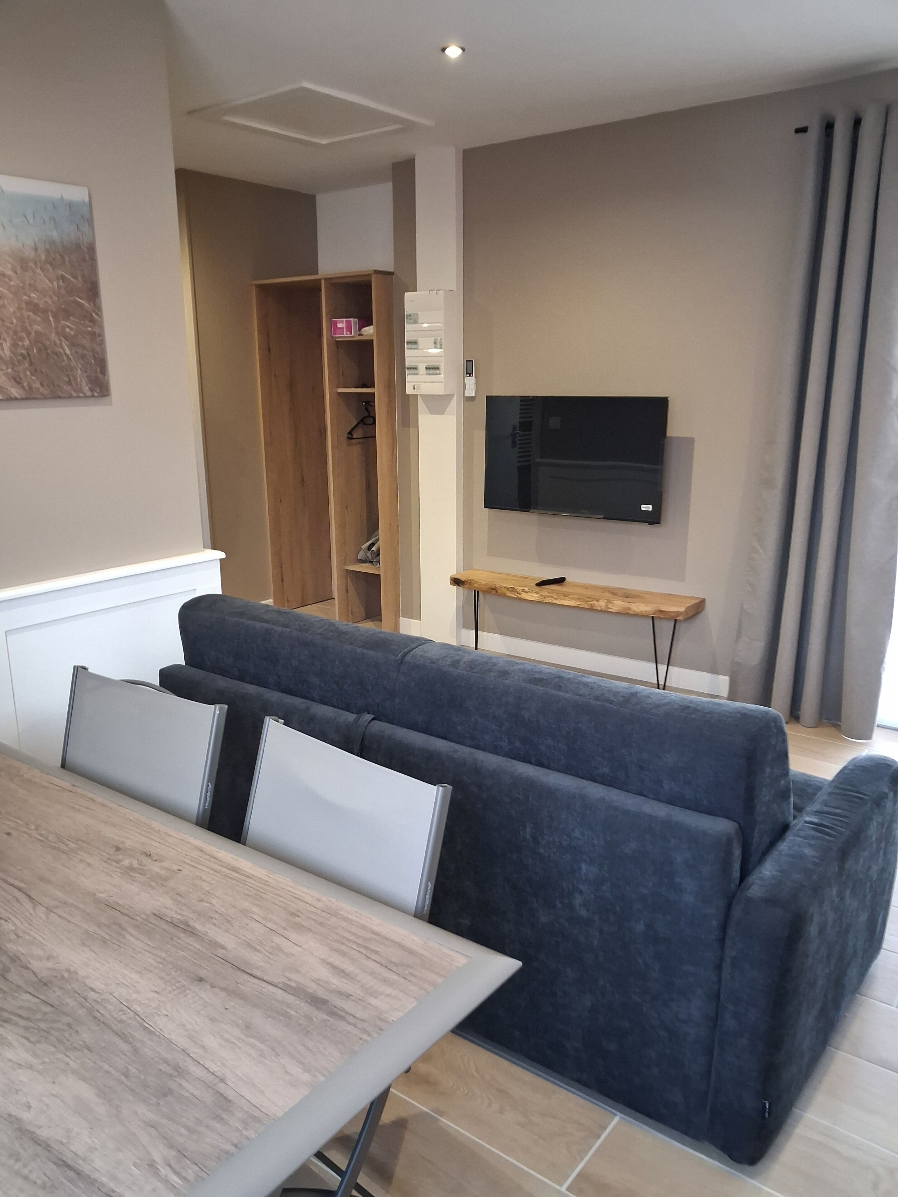 Een moderne woonkamer met een hoekbank, een flatscreen televisie aan de muur en een houten salontafel.