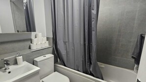 Un bagno con vasca, WC, lavandino e specchio.