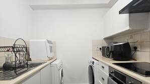 Una cucina compatta con microonde, lavatrice e macchina per il caffè.