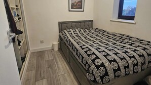 Una camera da letto con un letto, una finestra, una porta e un piccolo quadro appeso al muro.