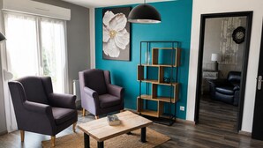 A modern living room with two armchairs, a coffee table, a pendant light, and a teal accent wall. - Le Clos de Candimalo (Epinal–Gérardmer route) (La Baffe)