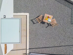 An outdoor seating area with a table and chairs, a small garden, and a building entrance. - Casa das Diogas by Galmi (Ponta do Sol)