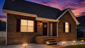 A brick house with a front porch, a welcome sign, and a number sign. - Close To The Action Outdoor Pool/ Close Main Strip (Pigeon Forge)