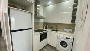 A compact kitchen with a refrigerator, oven, microwave, sink, and washing machine. - Cozy apartment with fantastic views of Las Vistas Beach (Arona)