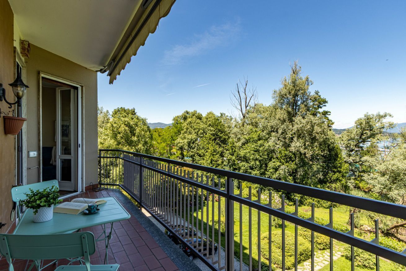 Een balkon met een tafel, stoelen en een bloempot.