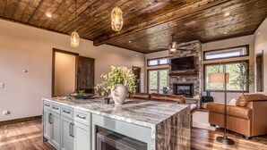 A spacious kitchen with a large island, a stone fireplace, and a leather sofa.