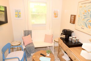 A cozy room with a bed, a coffee machine, a small table, a chair, and artwork on the walls. - Whispering Cove | Elegant Water View Retreat at Wilson Lake (Muscle Shoals)