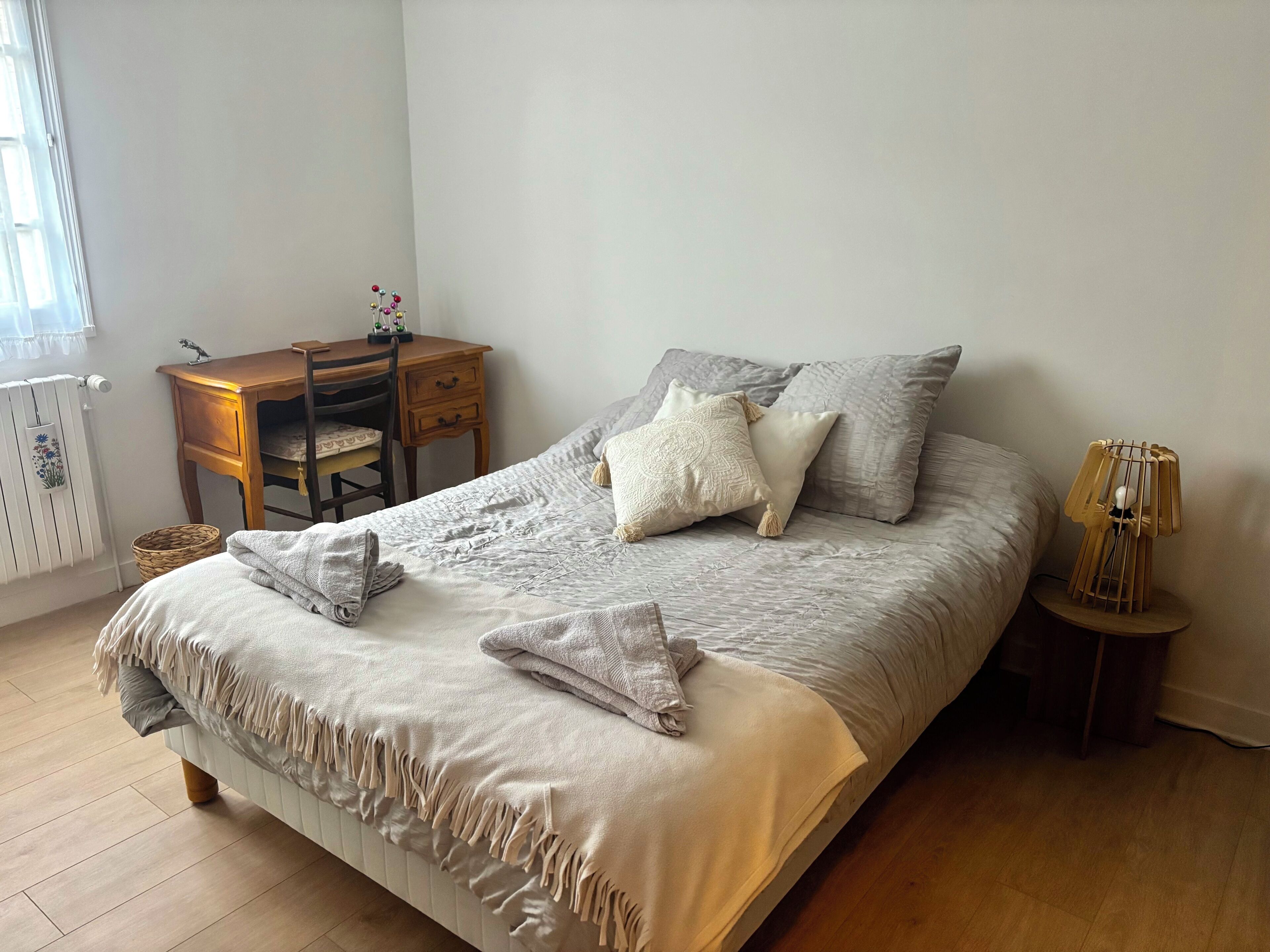 Une chambre à coucher comprenant un lit, un bureau, une chaise, une lampe et un radiateur.
