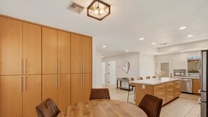 Una cucina moderna con mobili in legno, un tavolo da pranzo con sedie e un'isola con posti a sedere.