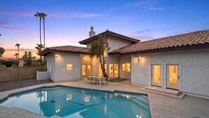 Una proprietà residenziale con piscina, mobili da patio e un esterno ben illuminato.