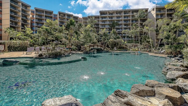 Un hotel con varios balcones, piscina y exuberante vegetación tropical.