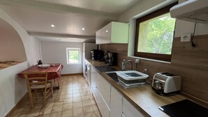Cocina compacta con mesa, lavamanos, cafetera y tostadora.