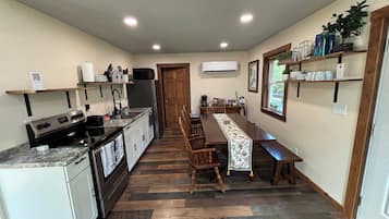 A compact kitchen with a central island, wooden chairs, a dining table, and a built-in oven.