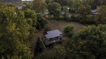 A large house with a spacious deck and a fenced yard surrounded by dense trees.