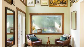A room with hardwood flooring, two leather armchairs, a large window, and a ceiling fan.